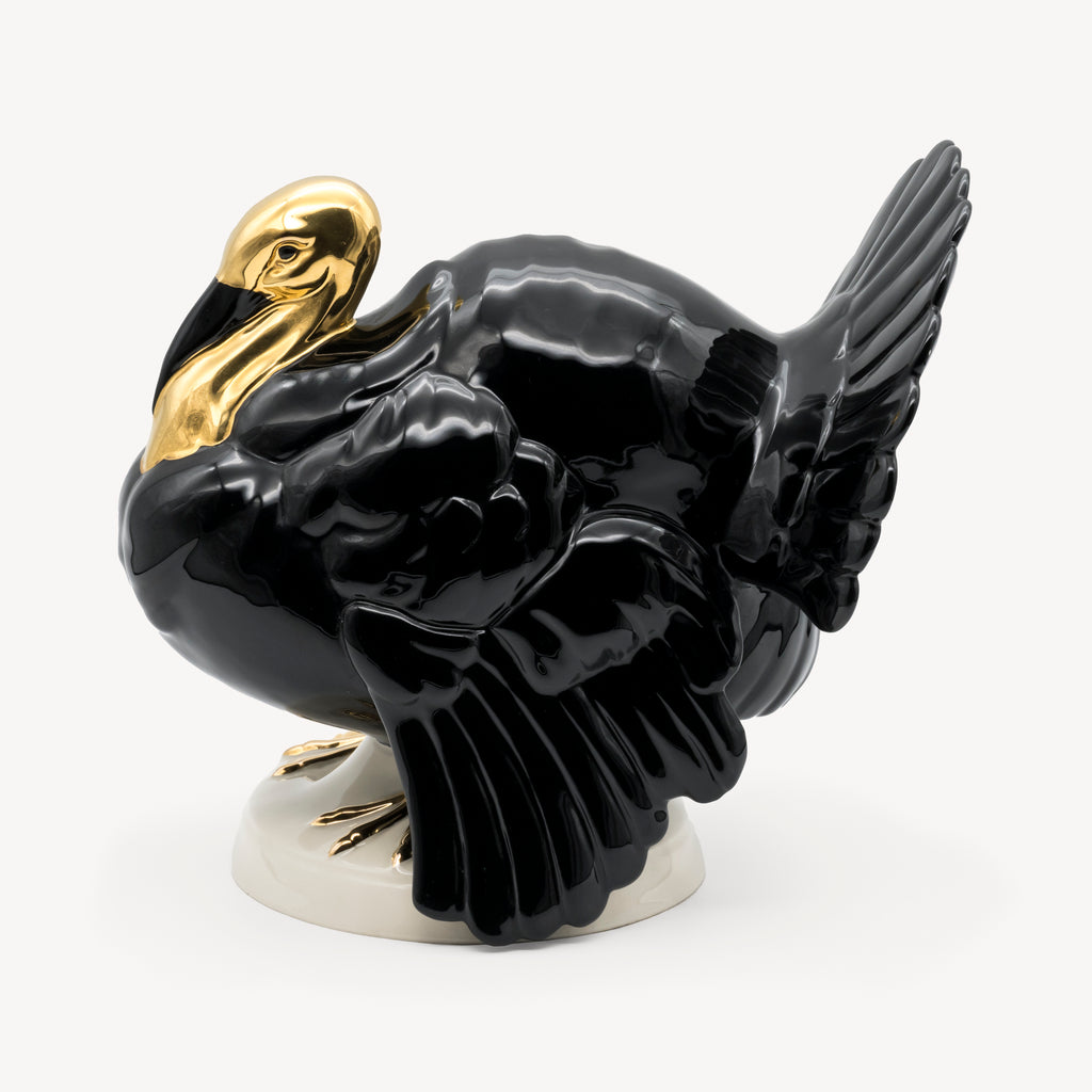 Side view of the Goebel porcelain turkey showing its glossy black body, layered wings and gold head.